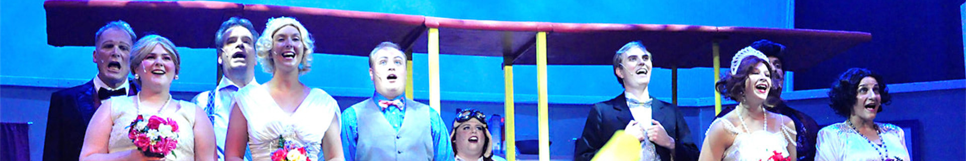 Cast singing in front of an airplane